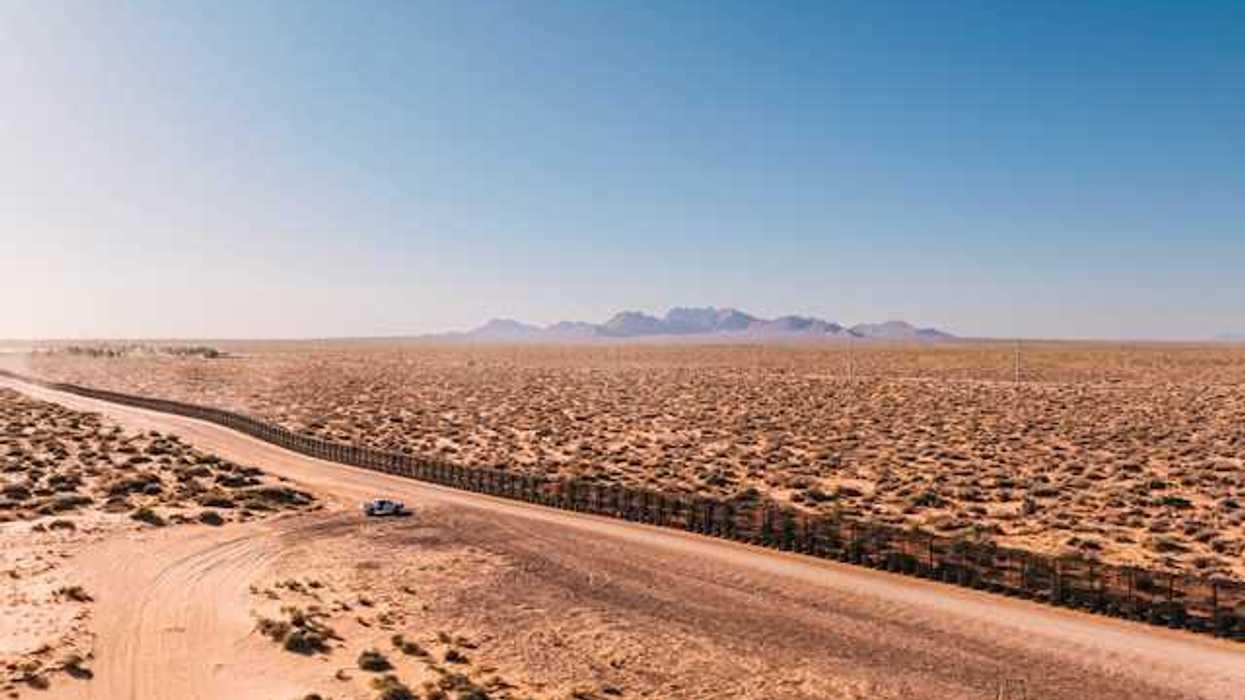 An aerial view of a dry, desert location with mountains the background