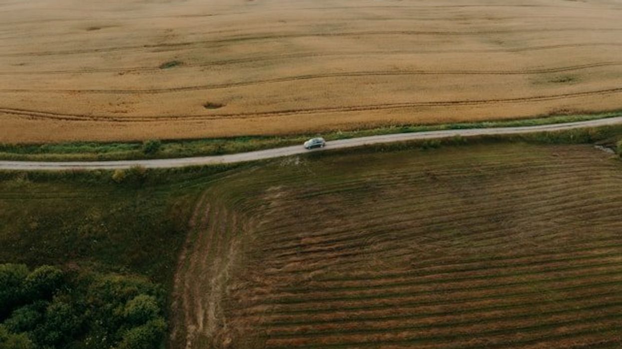 An aerial view of a farm field with a road next to it.