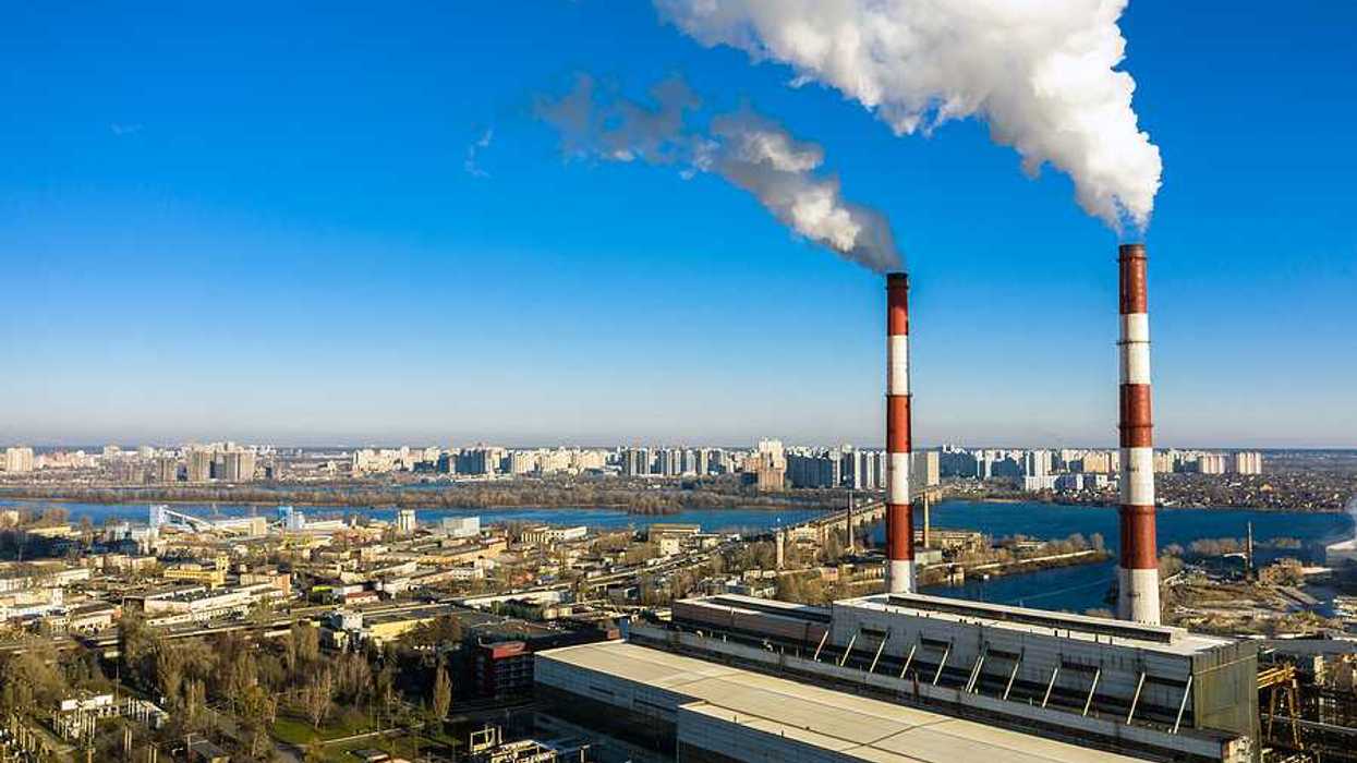 An aerial view of a garbage incinerator with smoke emitting from red and white smokestacks