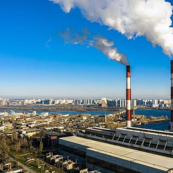 An aerial view of a garbage incinerator with smoke emitting from red and white smokestacks