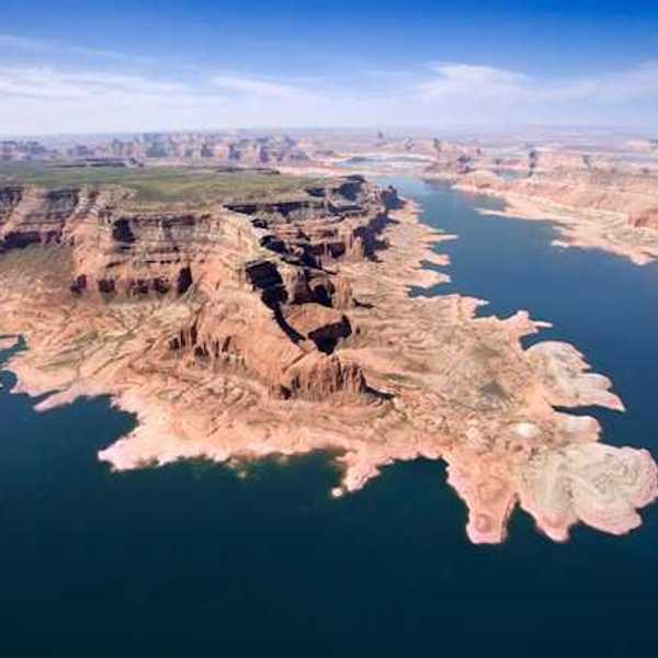 An aerial view of a lake stretching between dry bluffs in a desert landscape