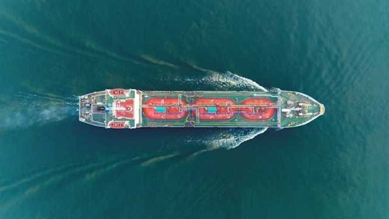 An aerial view of a large ship moving through green ocean water