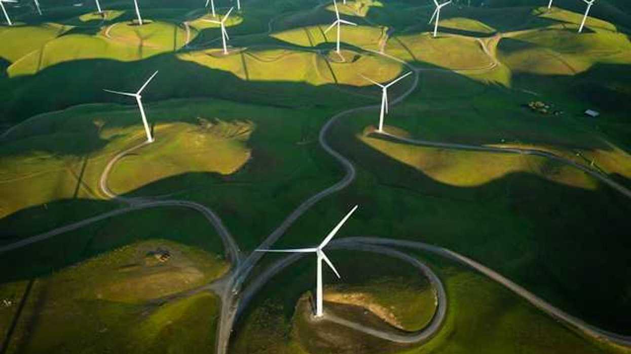 An aerial view of a log of wind turbines on a green hillside