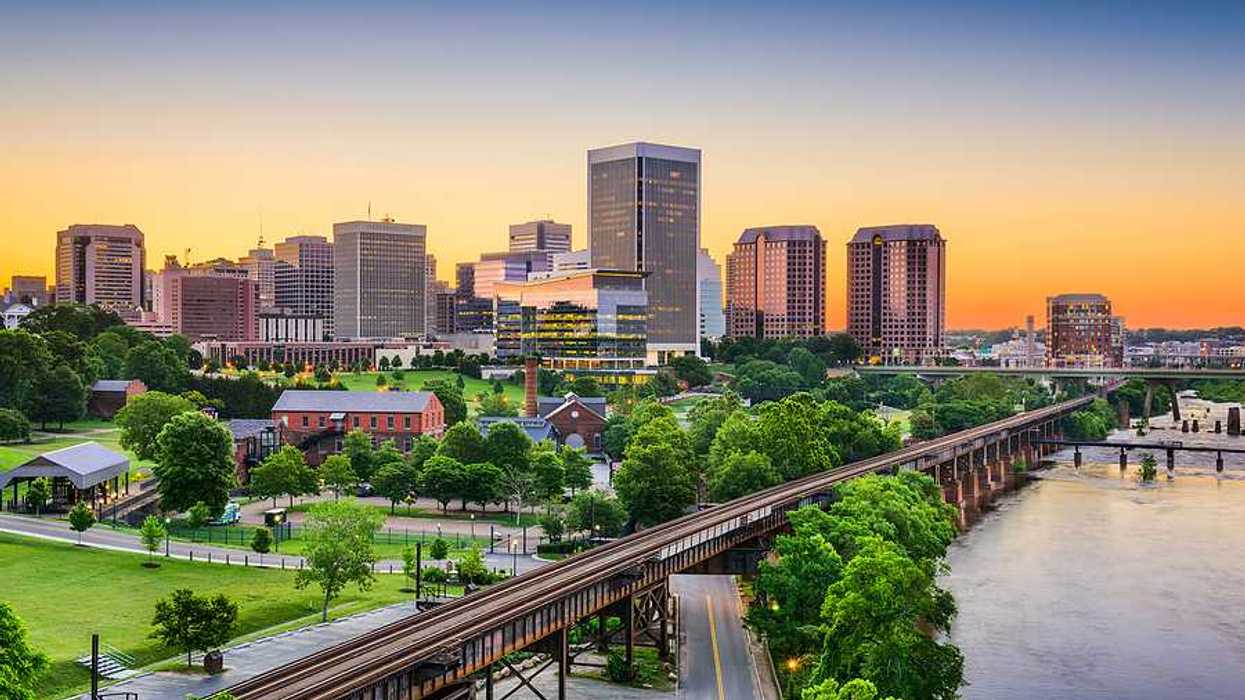 An aerial view of a railway and green trees with Richmond, VA in the background