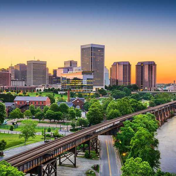 An aerial view of a railway and green trees with Richmond, VA in the background
