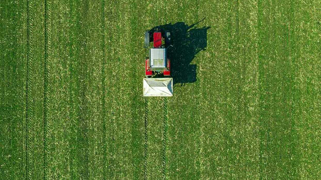 An aerial view of a red tractor driving across a field