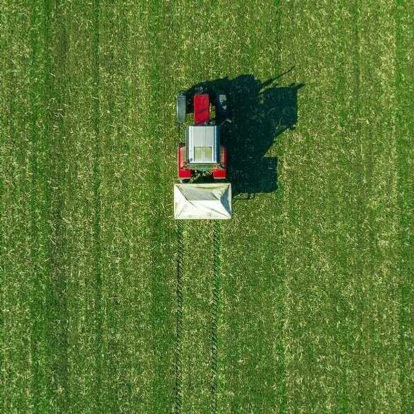 An aerial view of a red tractor driving across a field