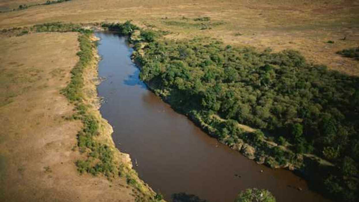 An aerial view of a river flowing between brown fields