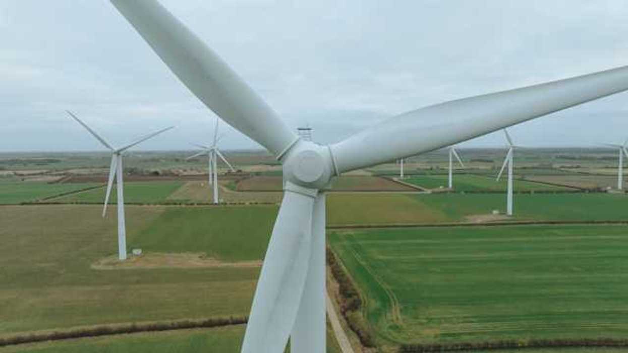 An aerial view of a row of wind turbines situated in a green field