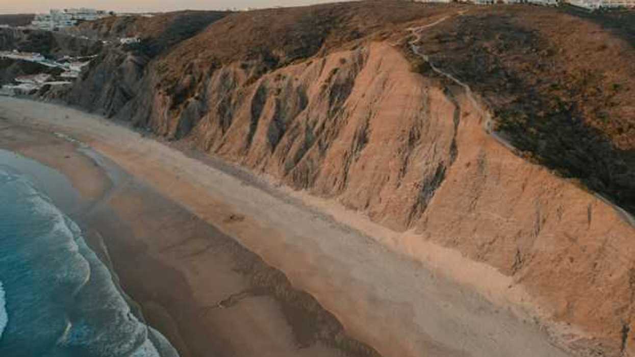 An aerial view of a sandy beach and a cliff