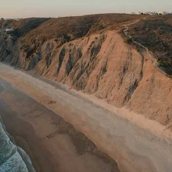 An aerial view of a sandy beach and a cliff