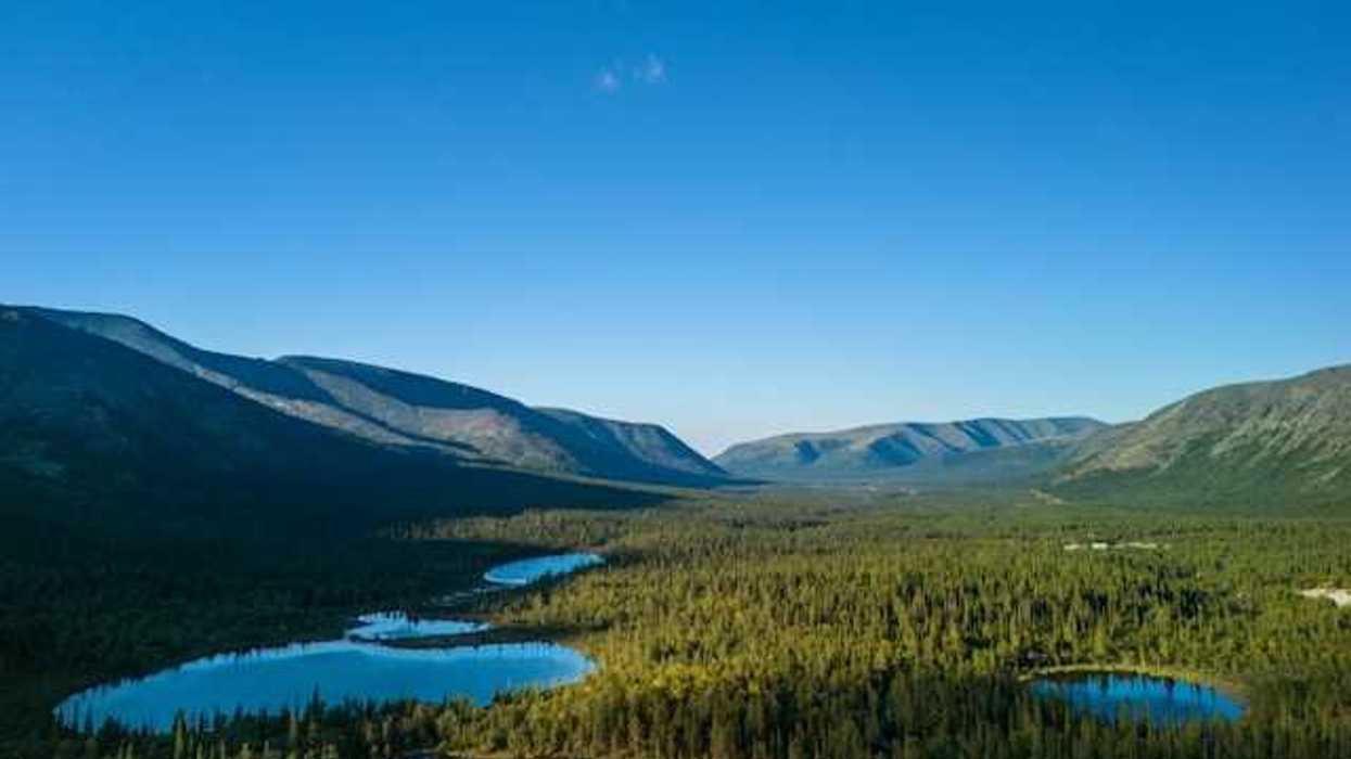 An aerial view of a series of lakes in the wilderness with mountains in the background