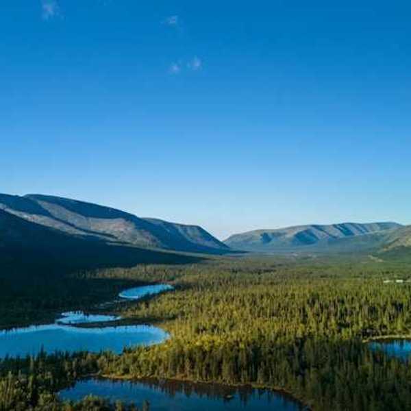 An aerial view of a series of lakes in the wilderness with mountains in the background