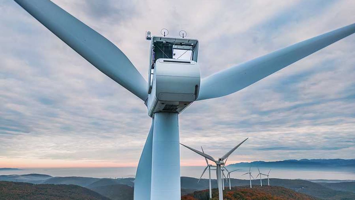 An aerial view of a set of wind turbines atop forested hills
