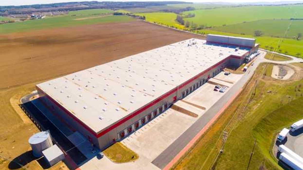 An aerial view of a warehouse building surrounded by green fields