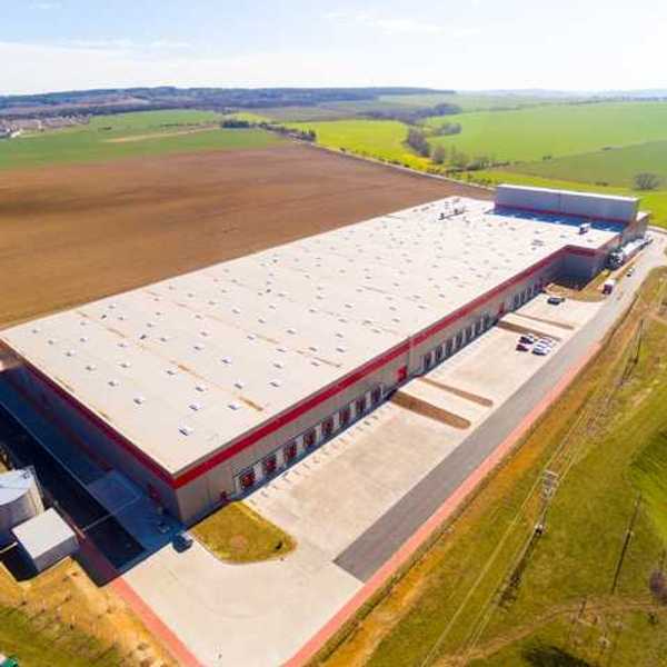 An aerial view of a warehouse building surrounded by green fields