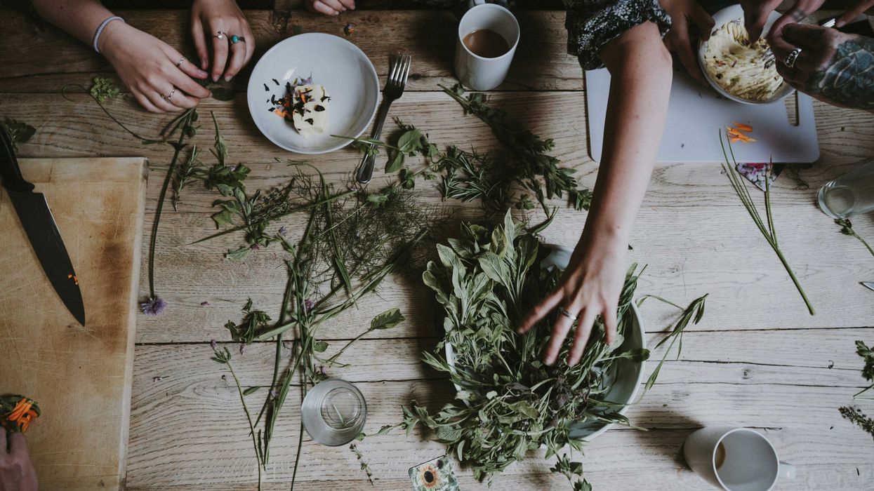 An aerial view of a wooden table with green stems being placed on plates