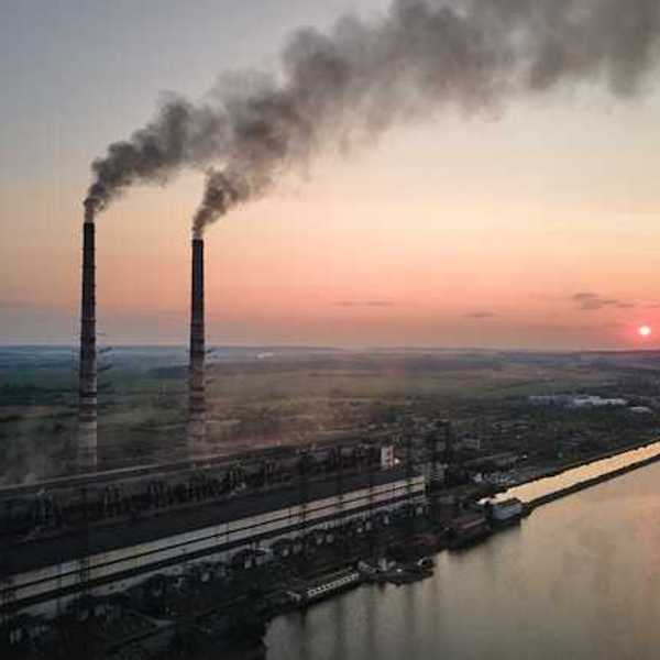 An aerial view of an industrial site with pollution streaming from smokestacks
