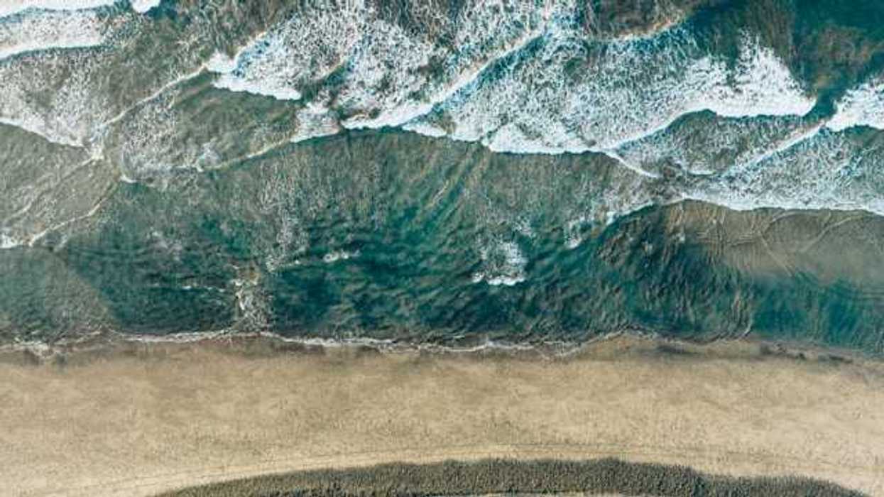 An aerial view of ocean waves hitting the beach