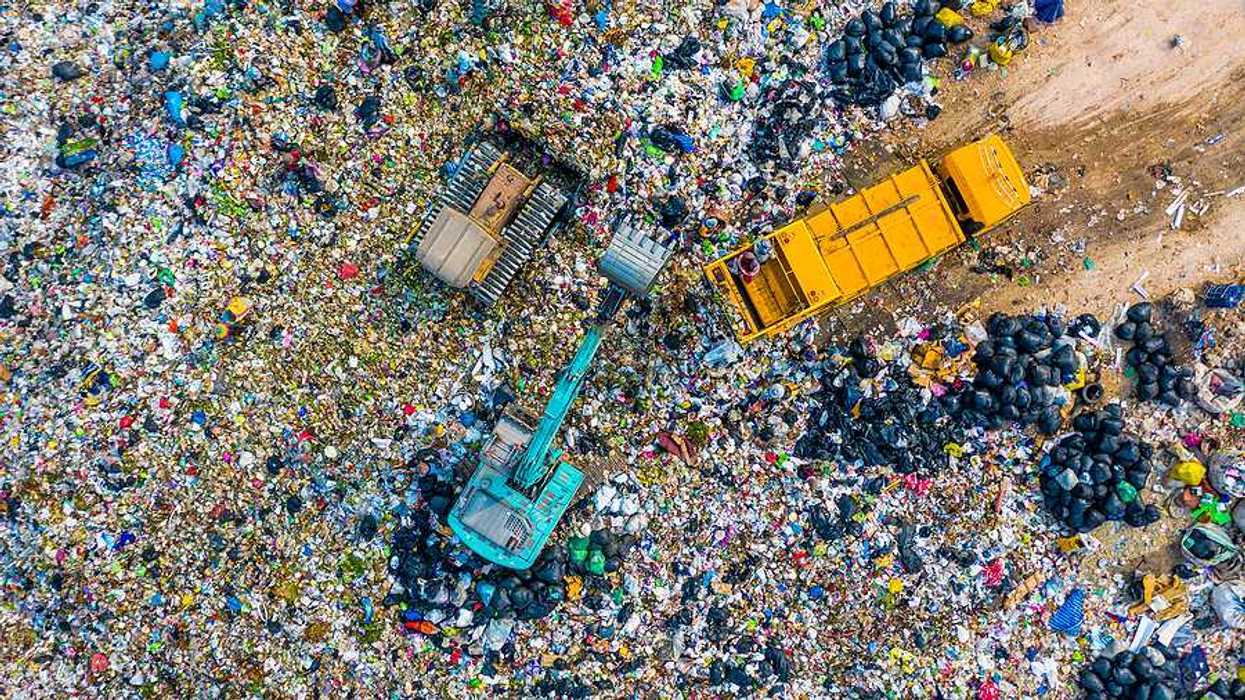 An aerial view of tractors and trucks leaving trash at a landfill
