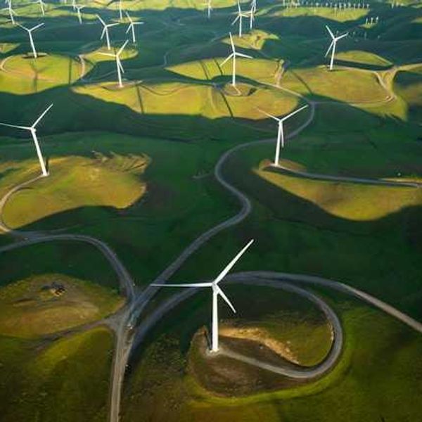 An aerial view of wind turbines sited on green hills