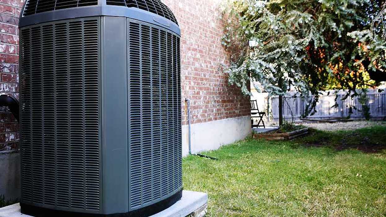 An air conditioning unit sitting next to a brick house
