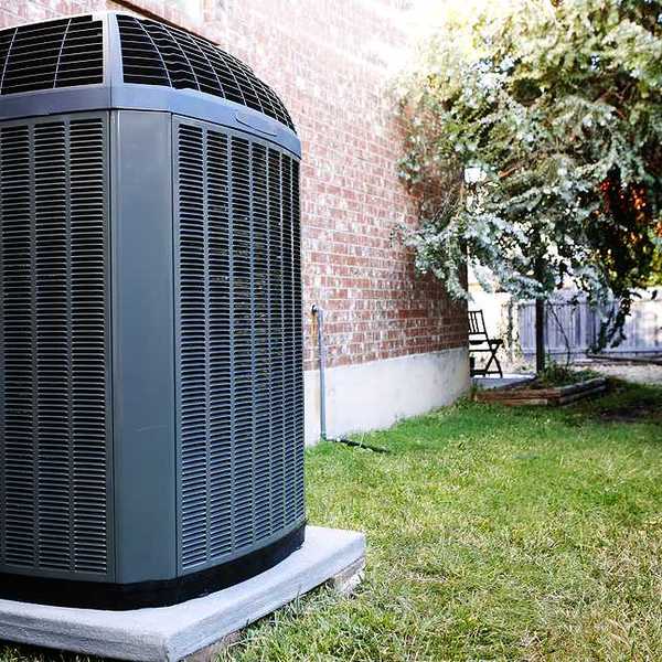 An air conditioning unit sitting next to a brick house