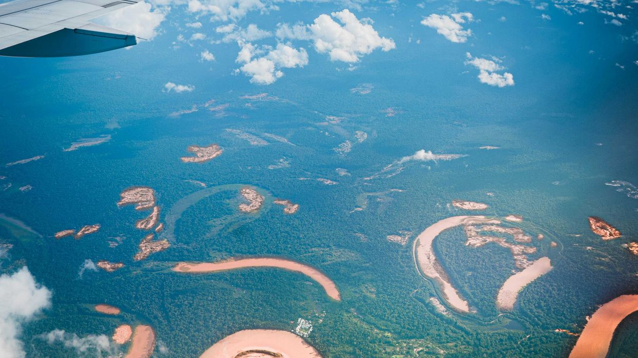 an airplane wing flying over a river and land.
