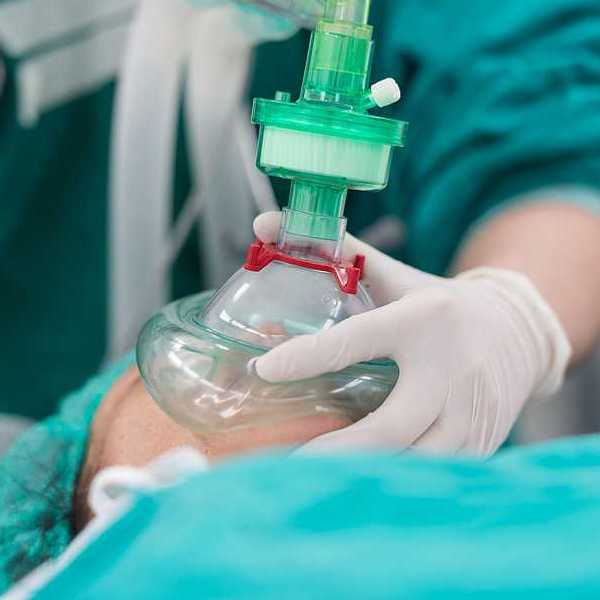 An anesthesiologist placing a cup on a patient's mouth