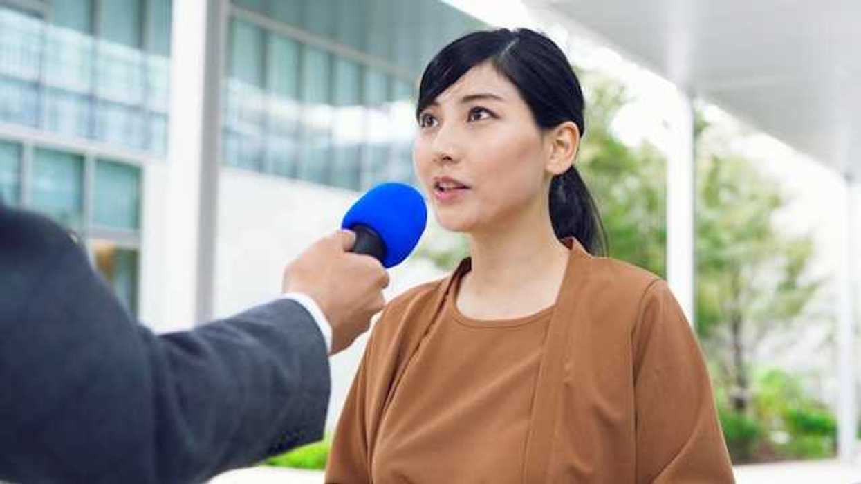An Asian woman being interviewed by a journalist