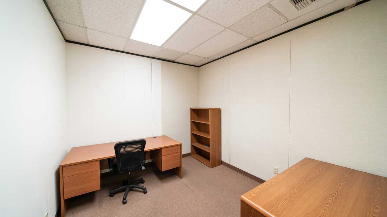 an empty office with a desk and a book shelf