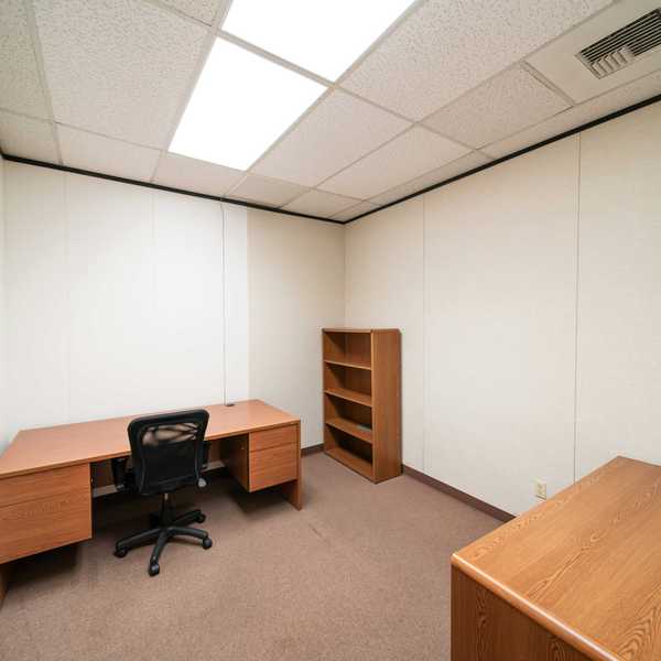 an empty office with a desk and a book shelf