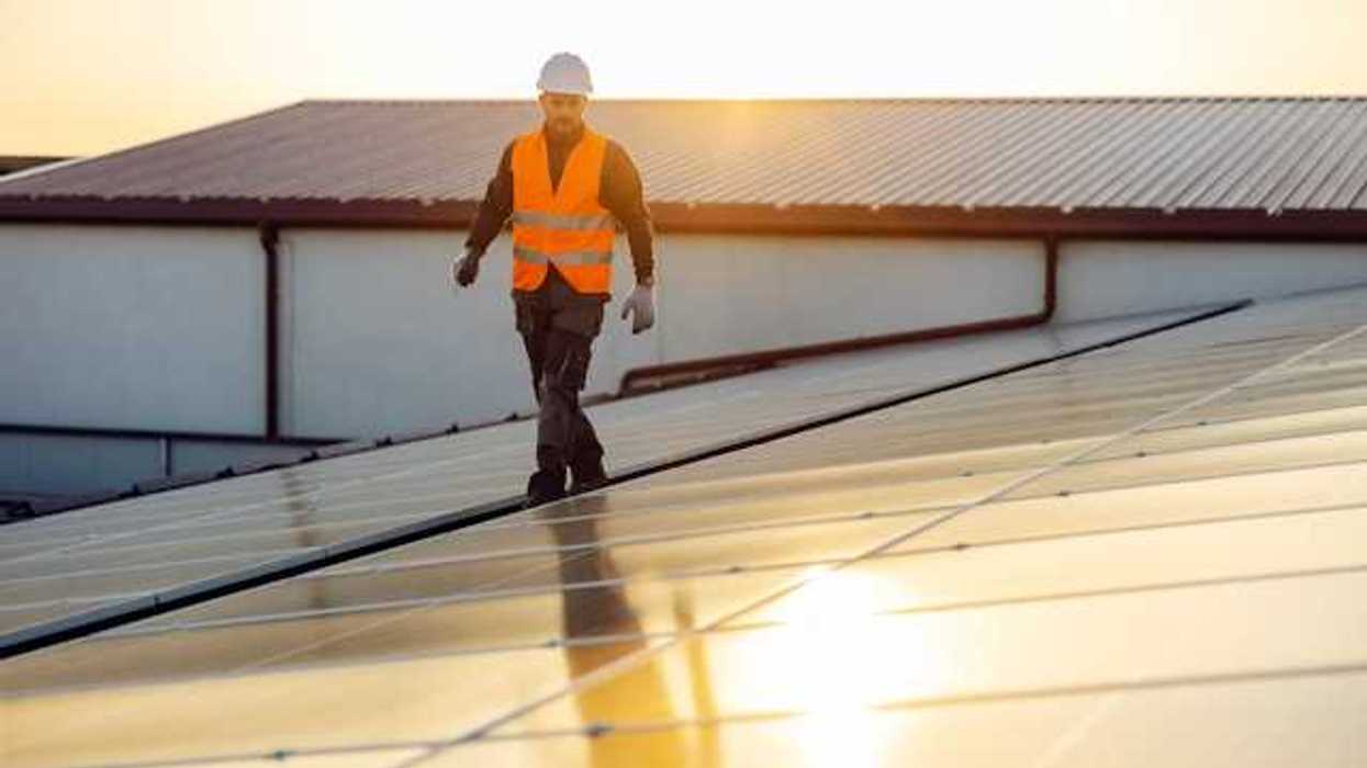 An energy worker inspecting rooftop solar panels