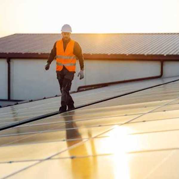 An energy worker inspecting rooftop solar panels