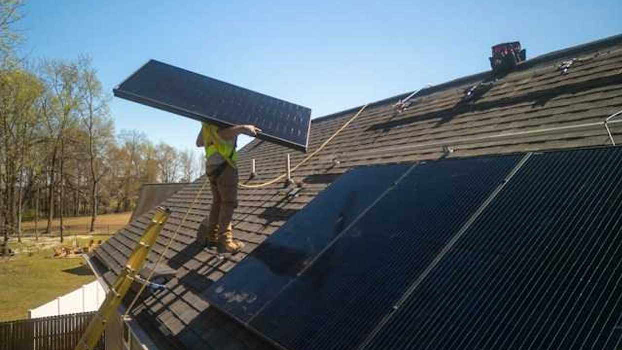 An energy worker placing solar panels on a roof