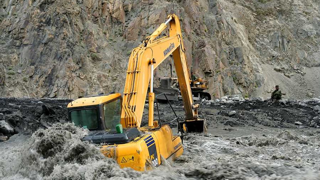 An excavator sitting on a flooded road in Pakistan
