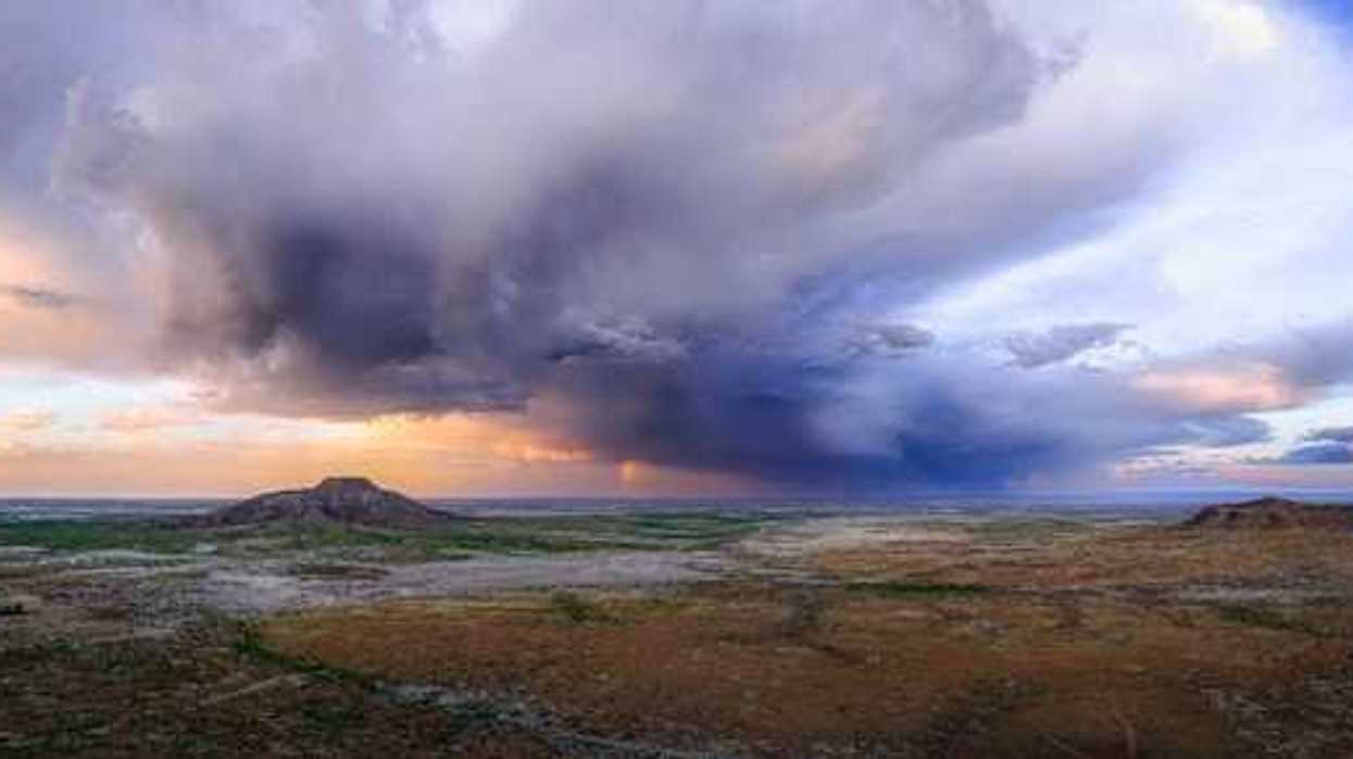 An expanse of desert with dark storm clouds building in the distance