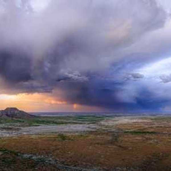 An expanse of desert with dark storm clouds building in the distance