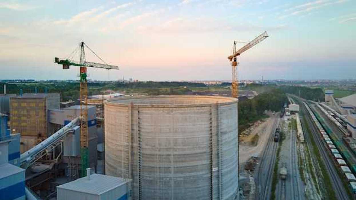 An industrial facility next to a railway system with a town in the background