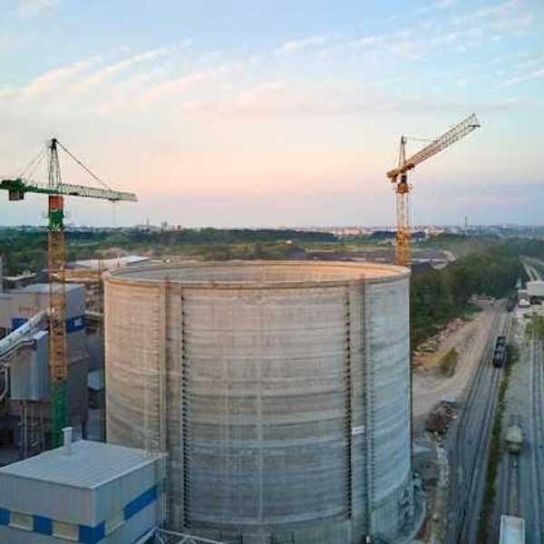 An industrial facility next to a railway system with a town in the background