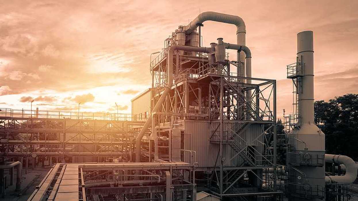 An industrial plant with the sun setting in the distance
