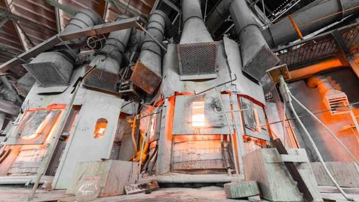 An industrial smelter with fire behind metal doors