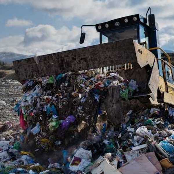 An industrial tractor moving piles of waste