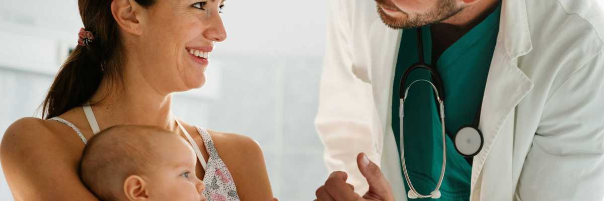 An infant holds a doctor's hand.