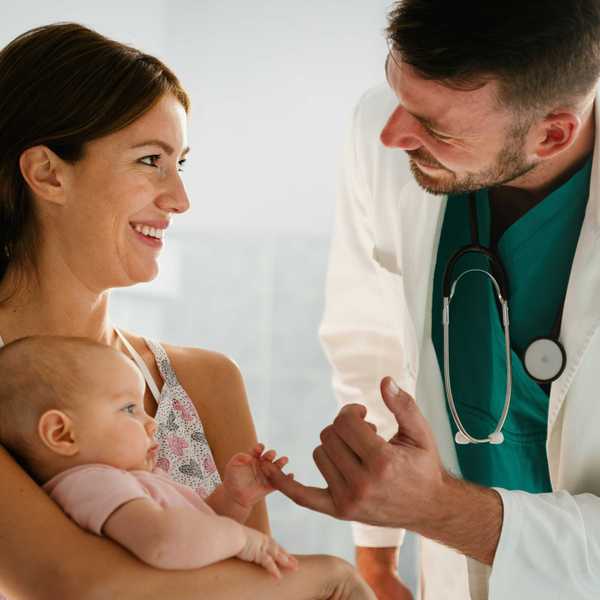 An infant holds a doctor's hand.