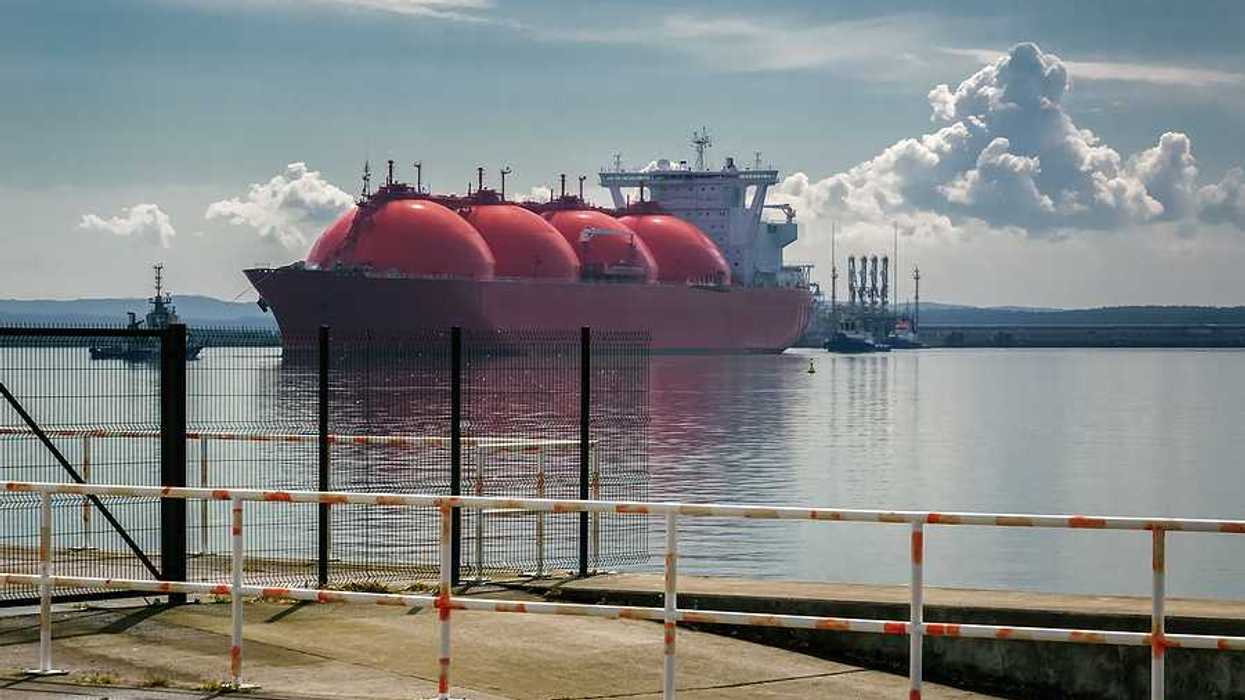 An LNG tanker ship and tugs are maneuvering for docking at a gas terminal