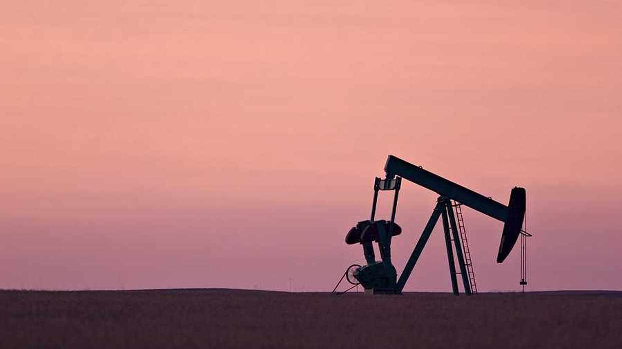 An oil drill pump jack against a sunset sky