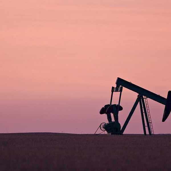 An oil drill pump jack against a sunset sky