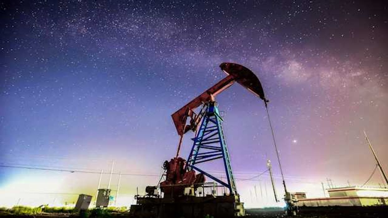 An oil drilling pump jack at night against a starry sky
