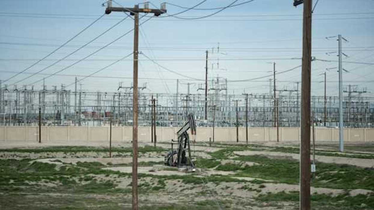 An oil pump jack in the midst of electrical poles and wires